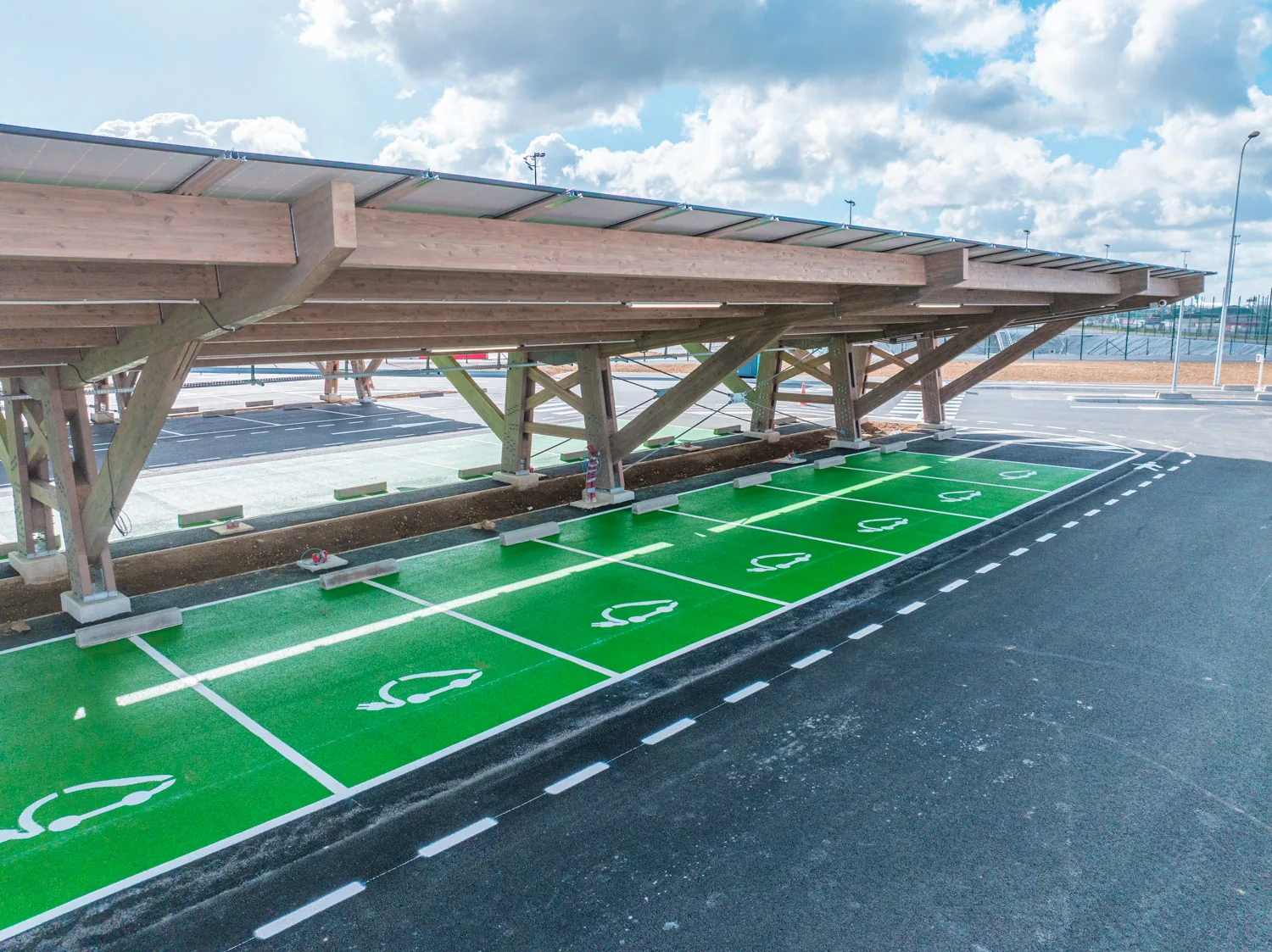 Structure en bois d’une ombrière photovoltaïque au-dessus de places de recharge électrique