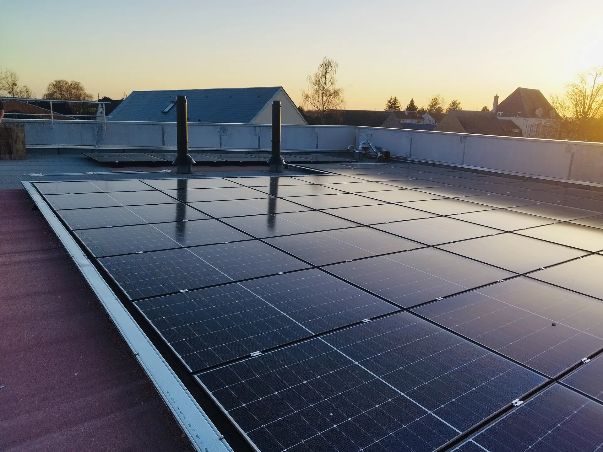 Centrale photovoltaïque installée sur une grande toiture-terrasse au coucher du soleil